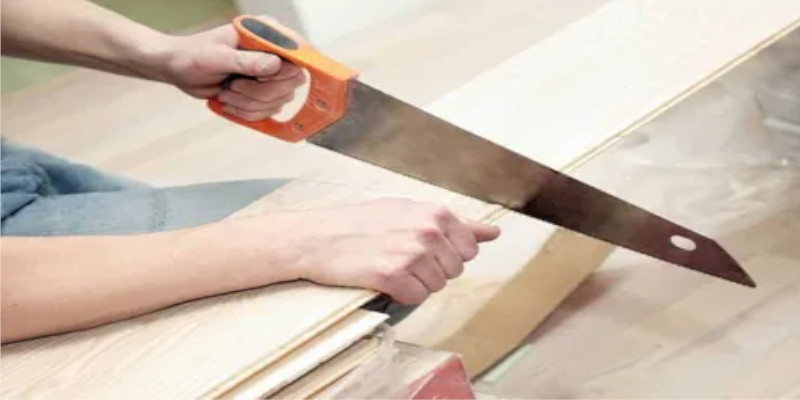 man cuts cedral board with hand saw