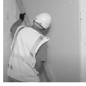 man is adjusting insulated plasterboard with a spirit level